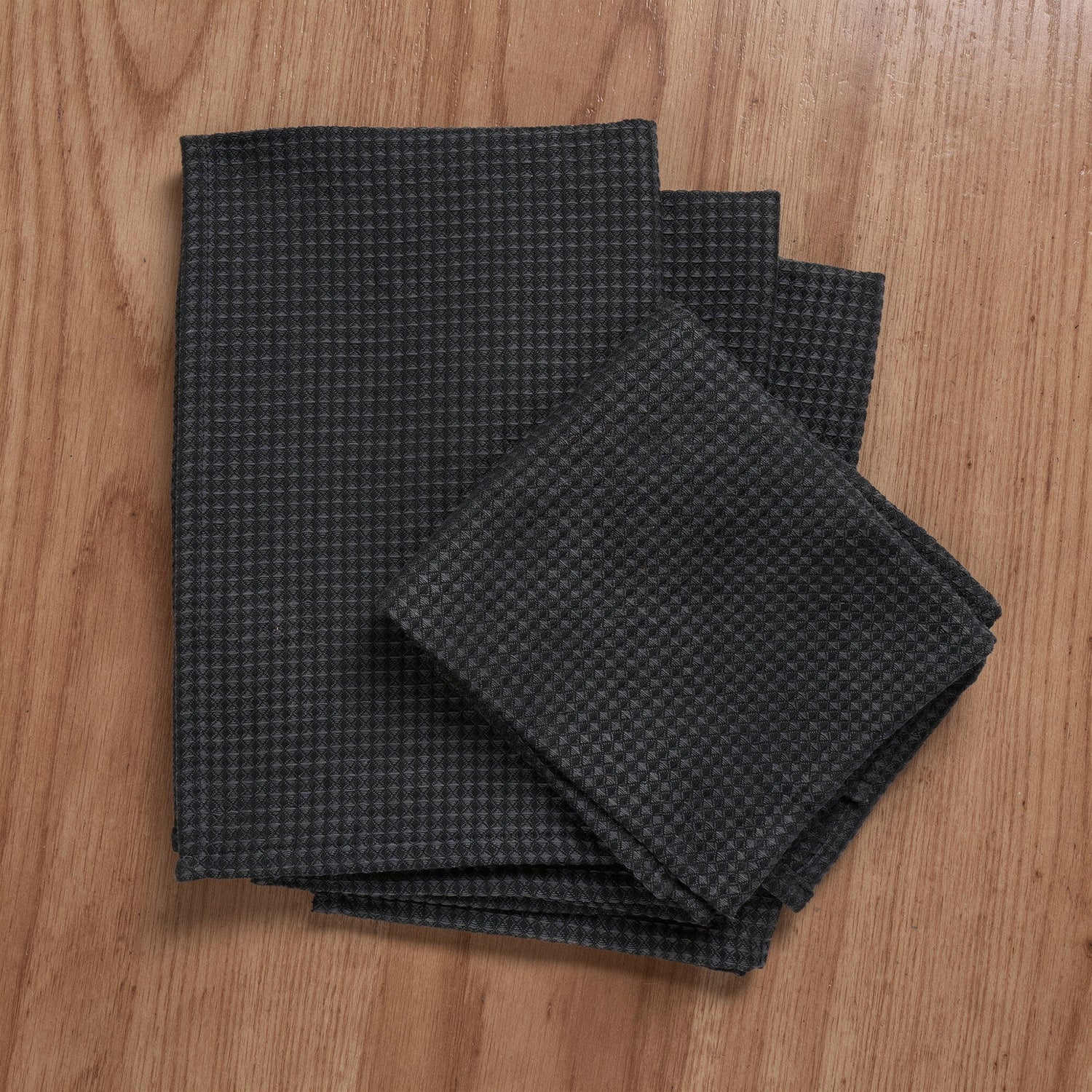 Waffle weave grey and black kitchen towels folded on a kitchen counter
