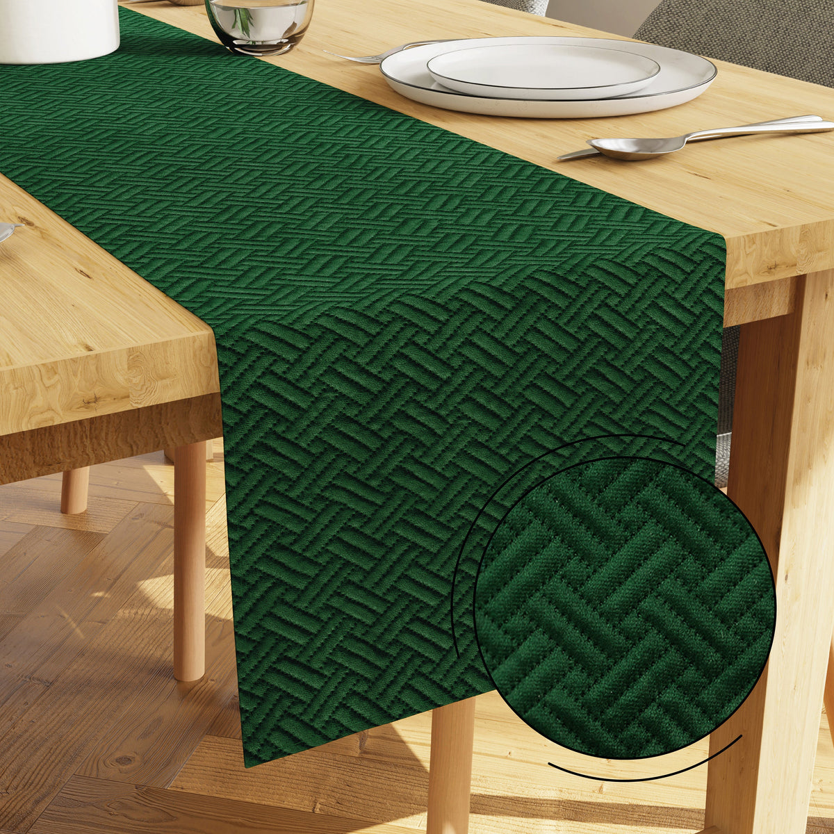 Forest green quilted velvet table runner on a light wood dining table with white plates