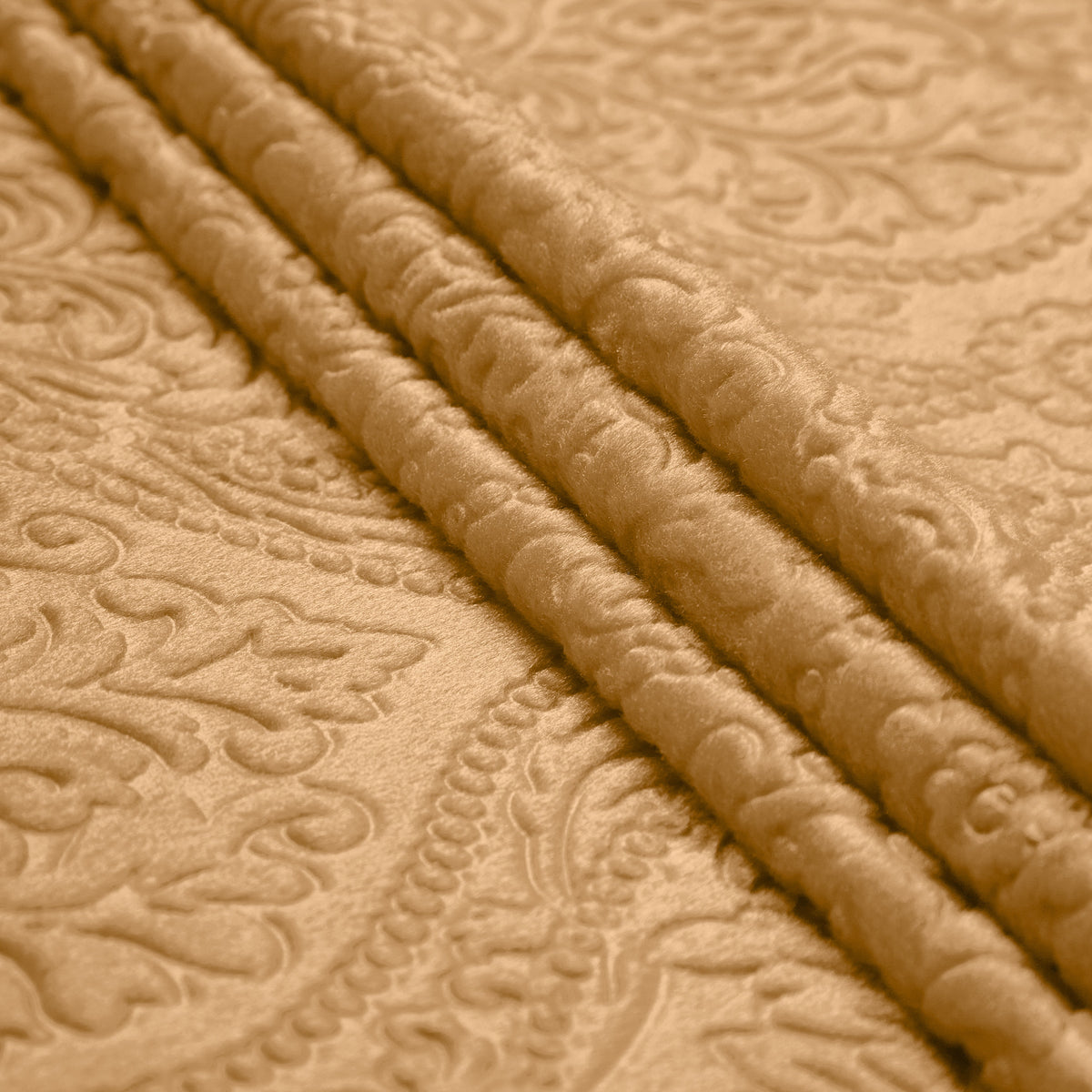 Champagne gold embossed velvet in parallel folds, the damask scrollwork showing as raised and flattened pile