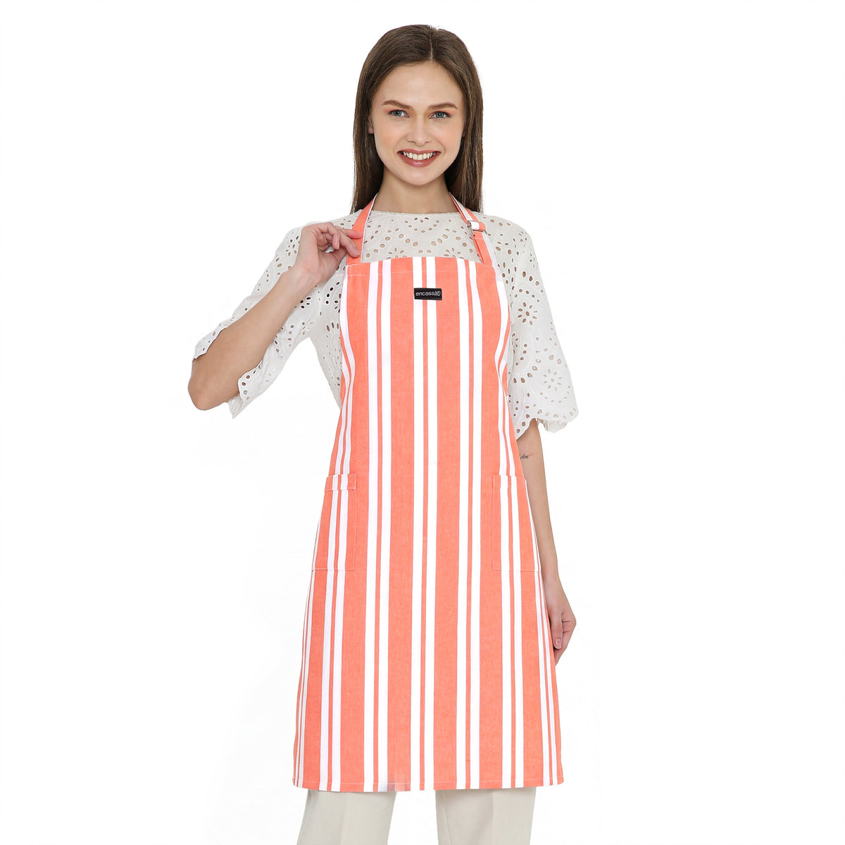 Coral and white striped cotton apron worn over a white eyelet blouse and cream trousers