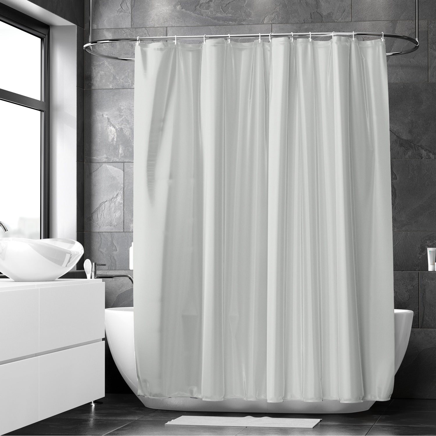 Light grey polyester shower curtain hanging on a rail above a white tub in a dark grey tiled bathroom