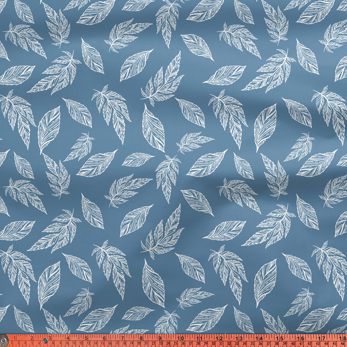 Blue cotton printed with white leaves, an inch and centimetre tape laid across the bottom edge of the cloth
