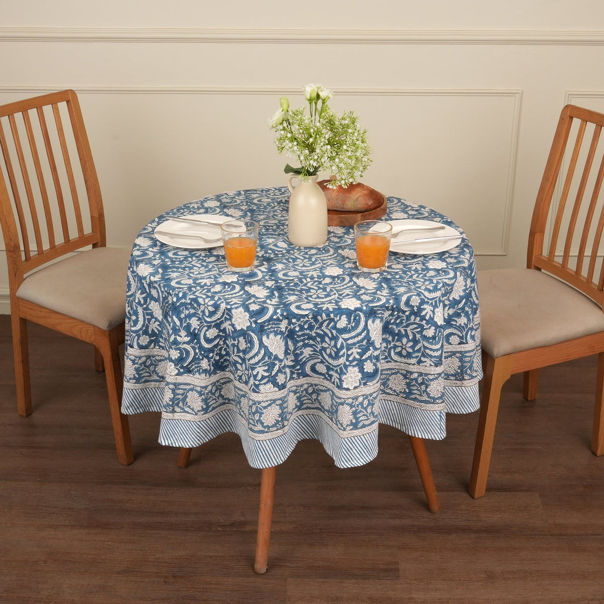 Indigo block print round table cover on a small wooden round table set for two with juice and flowers