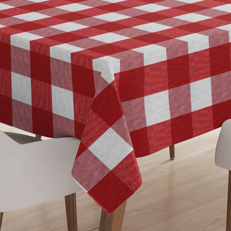 Red and white buffalo check cotton tablecloth hanging over the corner of a table, white chairs beside it