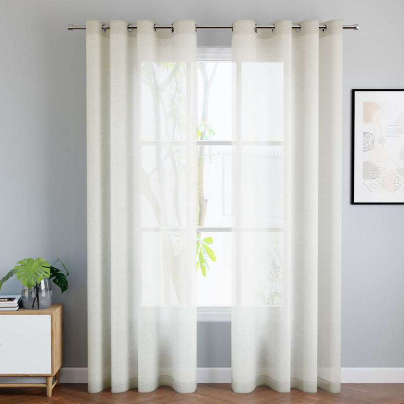 Floor-length cream sheer curtains framing a tall window in a styled living room
