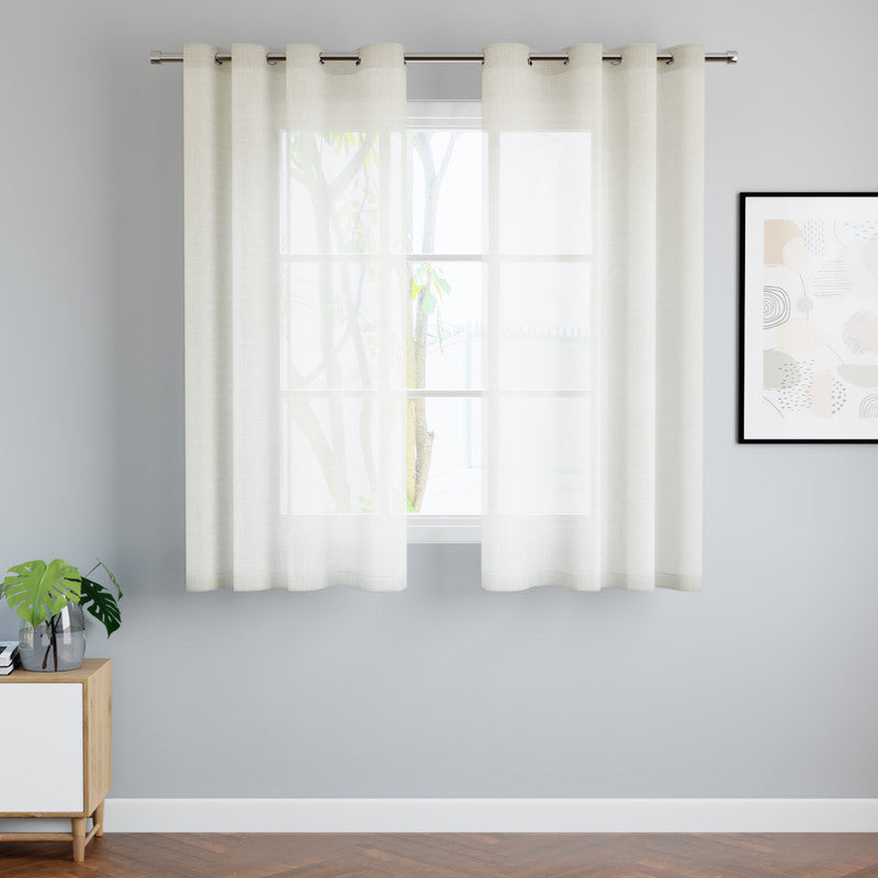 Cream cotton sheer curtain panels gathered into soft folds at a bright window