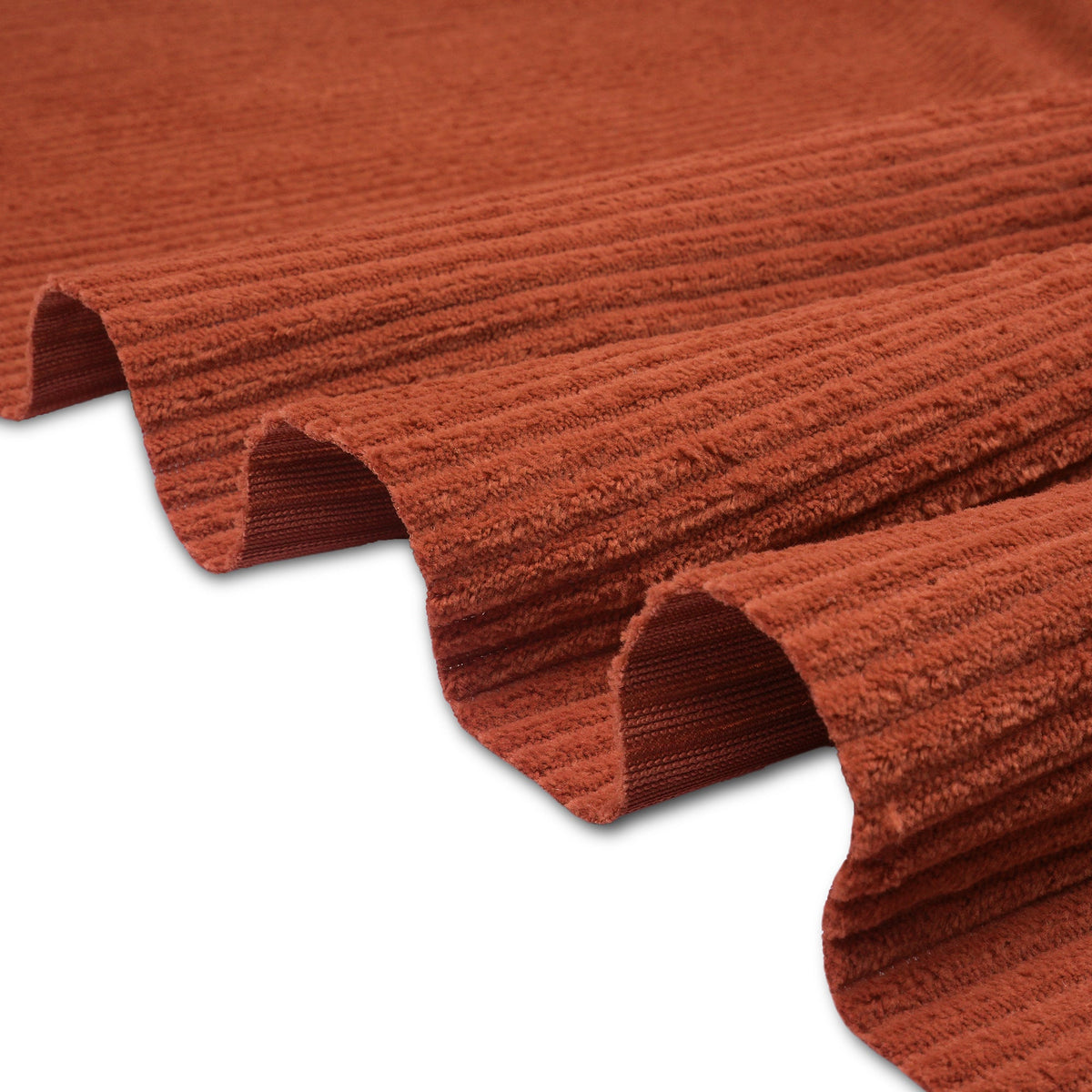 Rust corduroy folded into deep waves, its ribbed wales catching the light