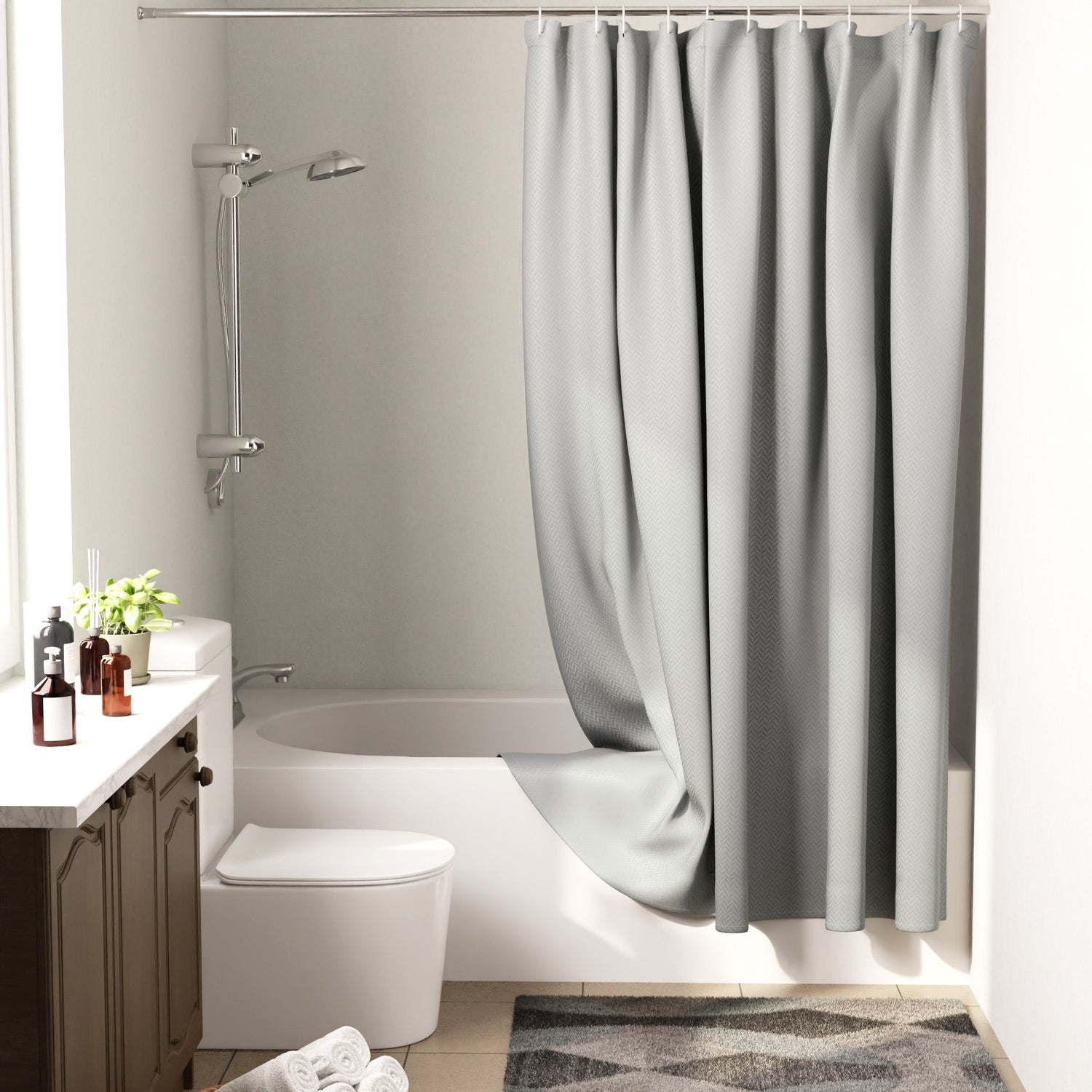 Light grey polyester shower curtain hanging on a rod in a modern bathroom with a bathmat on the tiled floor