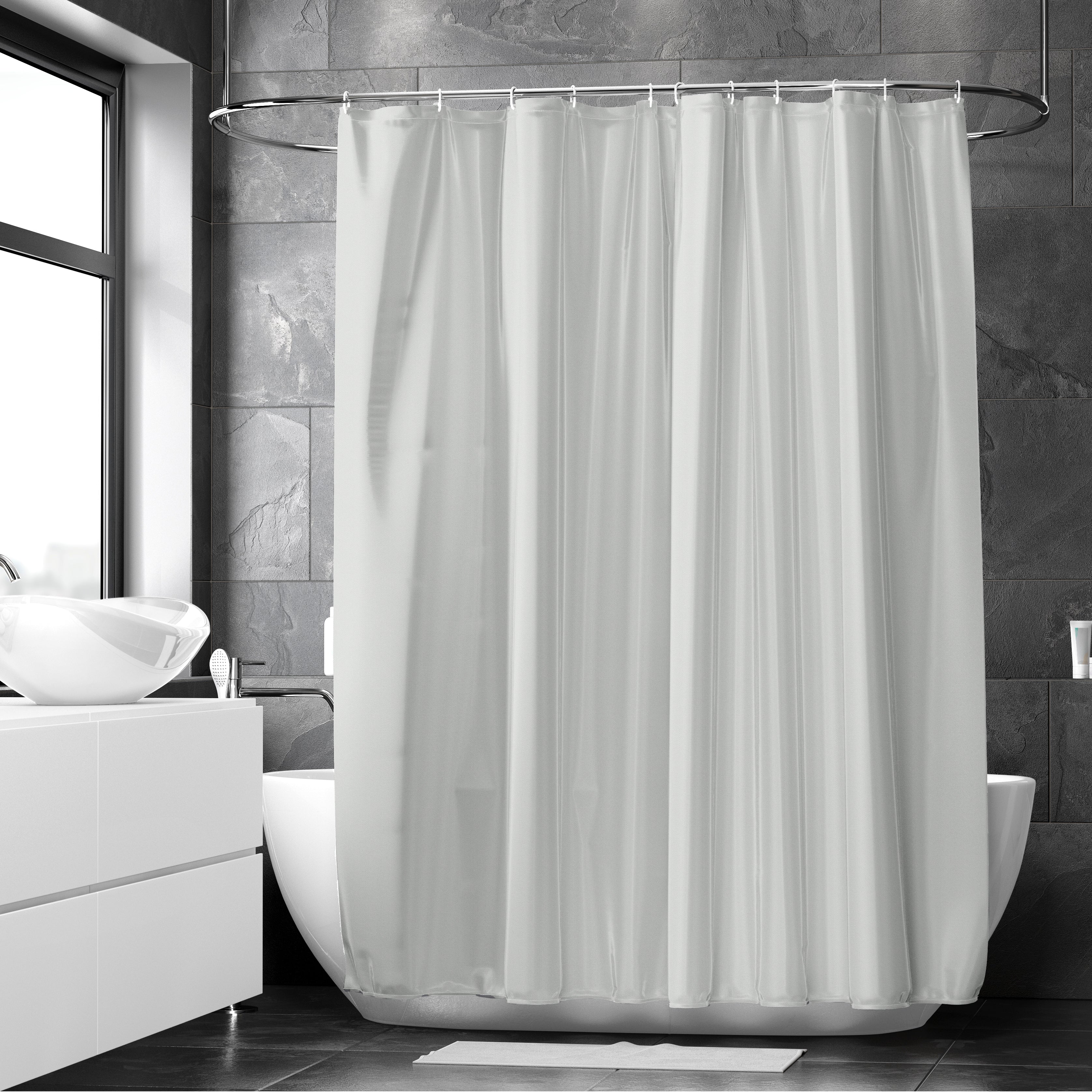 Light grey polyester shower curtain hanging on a rail above a white tub in a dark grey tiled bathroom