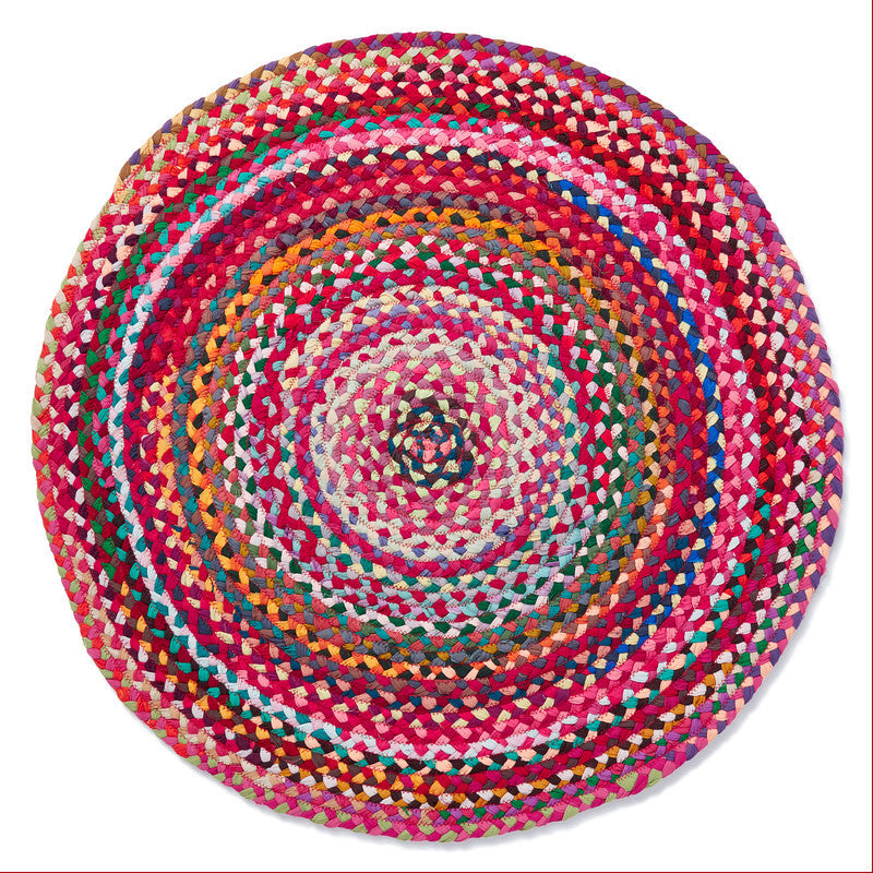 Round chindi rag rug, pink and red fabric strips flecked with green and orange, braided in rings