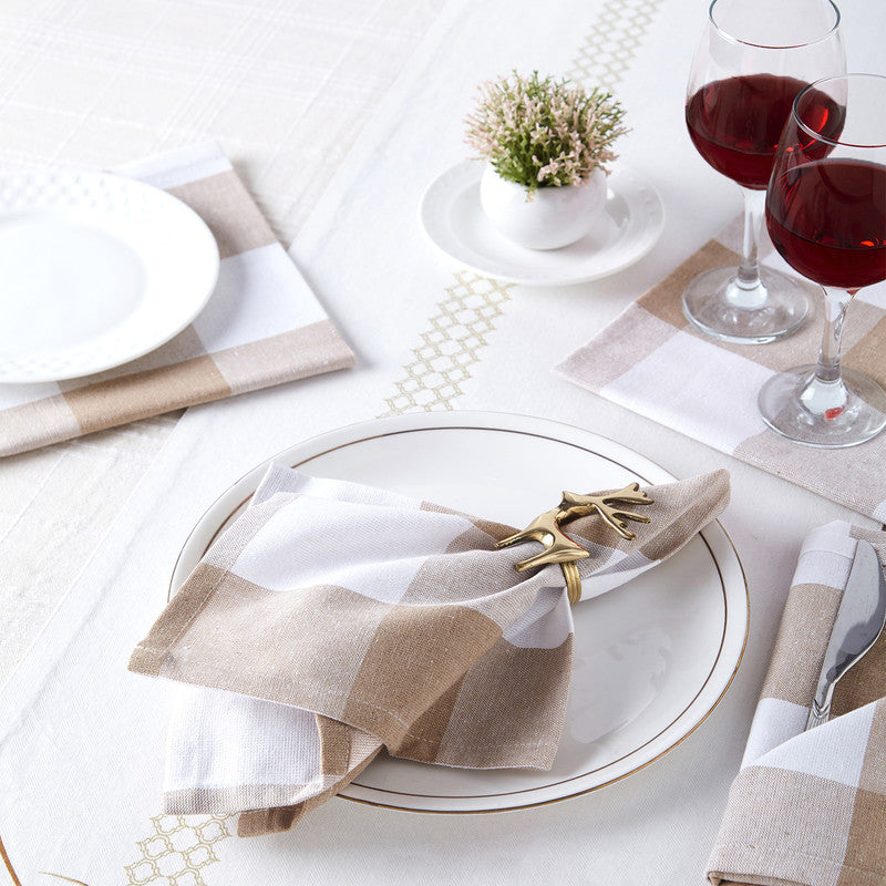 Beige and white check cotton napkin held by a gold ring on a gold-rimmed plate, with red wine glasses
